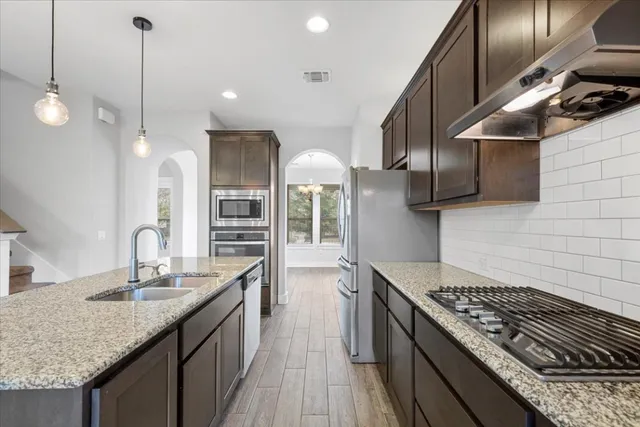 a kitchen with stainless steel appliances granite countertop a stove a sink and a refrigerator