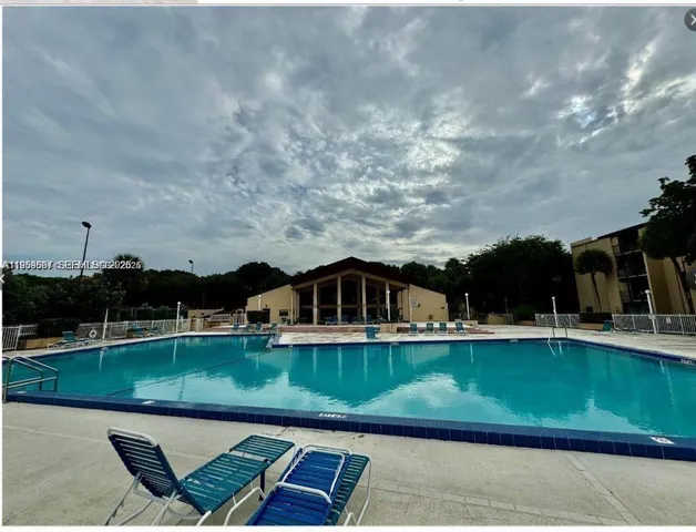 a view of a swimming pool with lawn chairs and plants