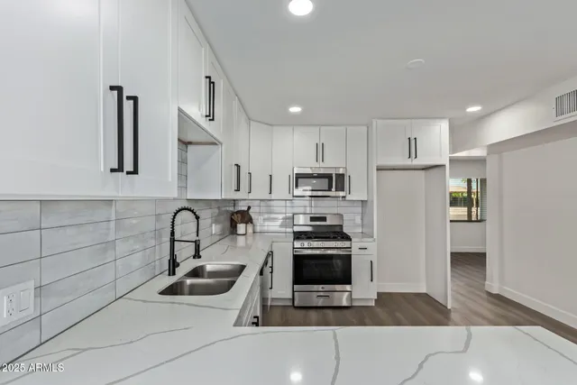 a kitchen with stainless steel appliances a stove a sink and a refrigerator