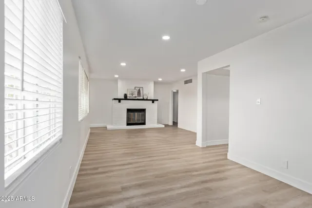 a view of empty room with wooden floor and fireplace