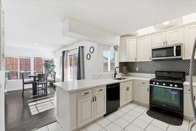 a kitchen with stainless steel appliances granite countertop a stove top oven a sink dishwasher and white cabinets