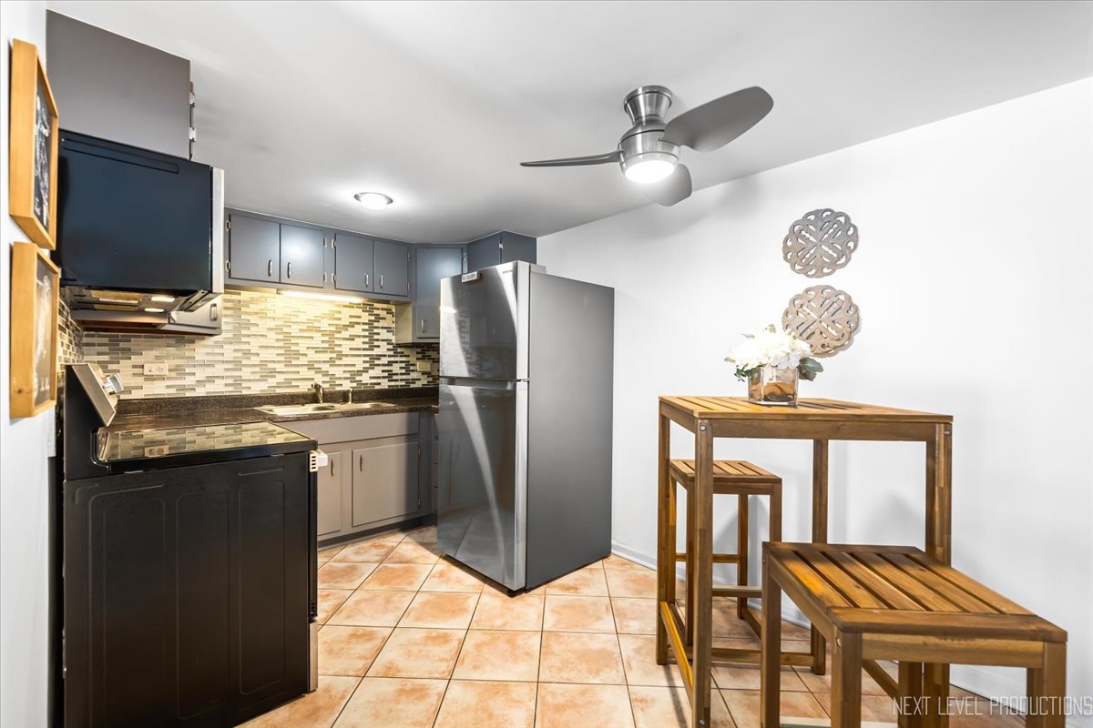 127 North Wolf Road, Unit 60A Wheeling, IL 60090 - Photo 7 of 22 a kitchen with stainless steel appliances kitchen island granite countertop a refrigerator a stove a microwave oven with white cabinets and wooden floor