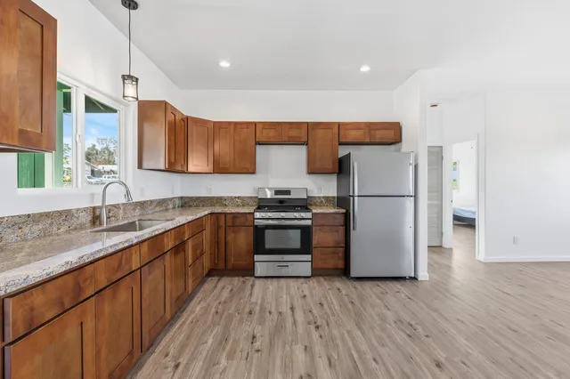 a kitchen with a refrigerator a sink and wooden floor