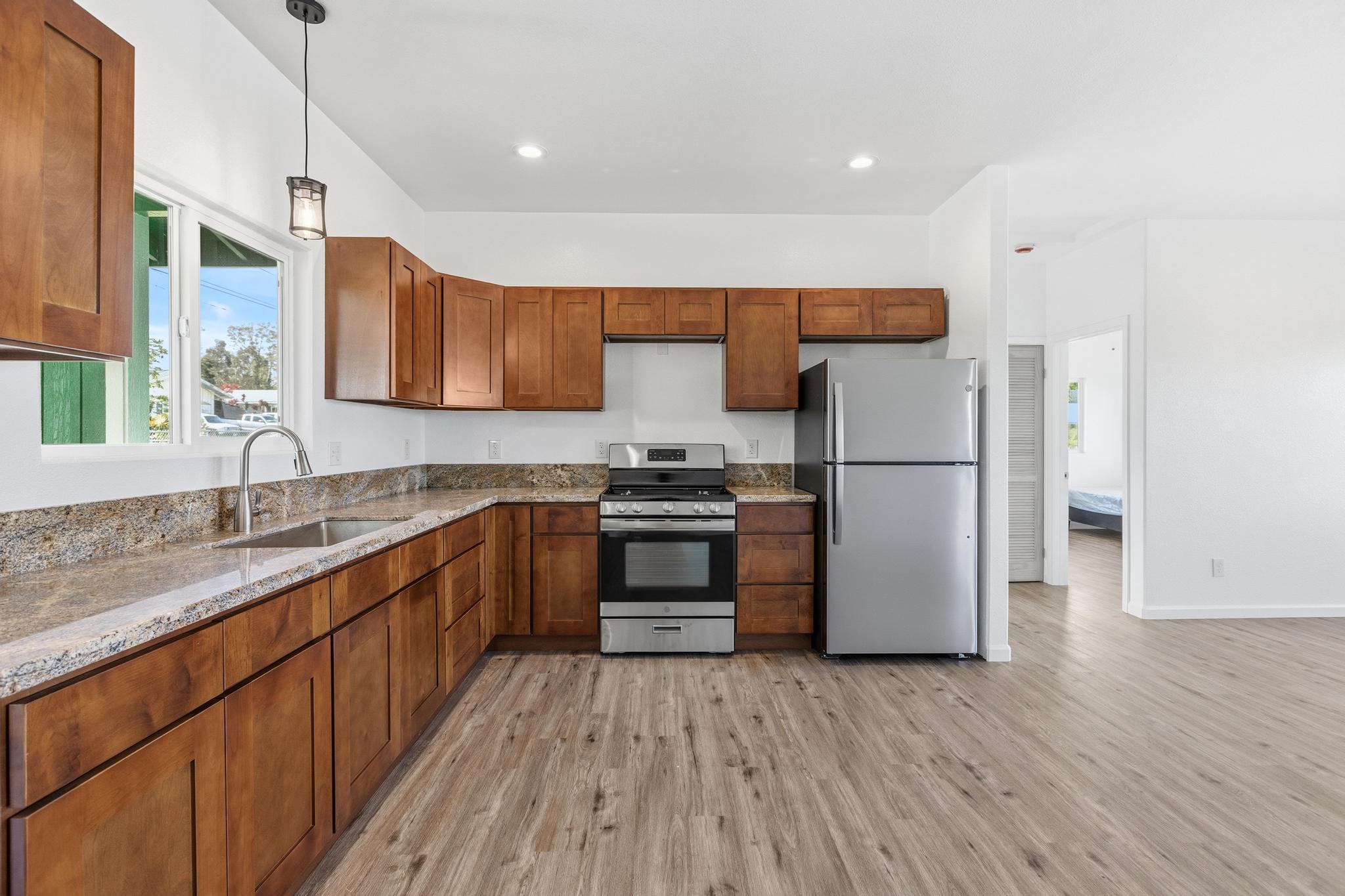 18-7842 Kaniela Road Mountain View, HI 96771 - Photo 11 of 30 a kitchen with a refrigerator a sink and wooden floor
