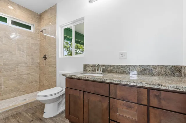 a bathroom with a granite countertop sink toilet a mirror and shower