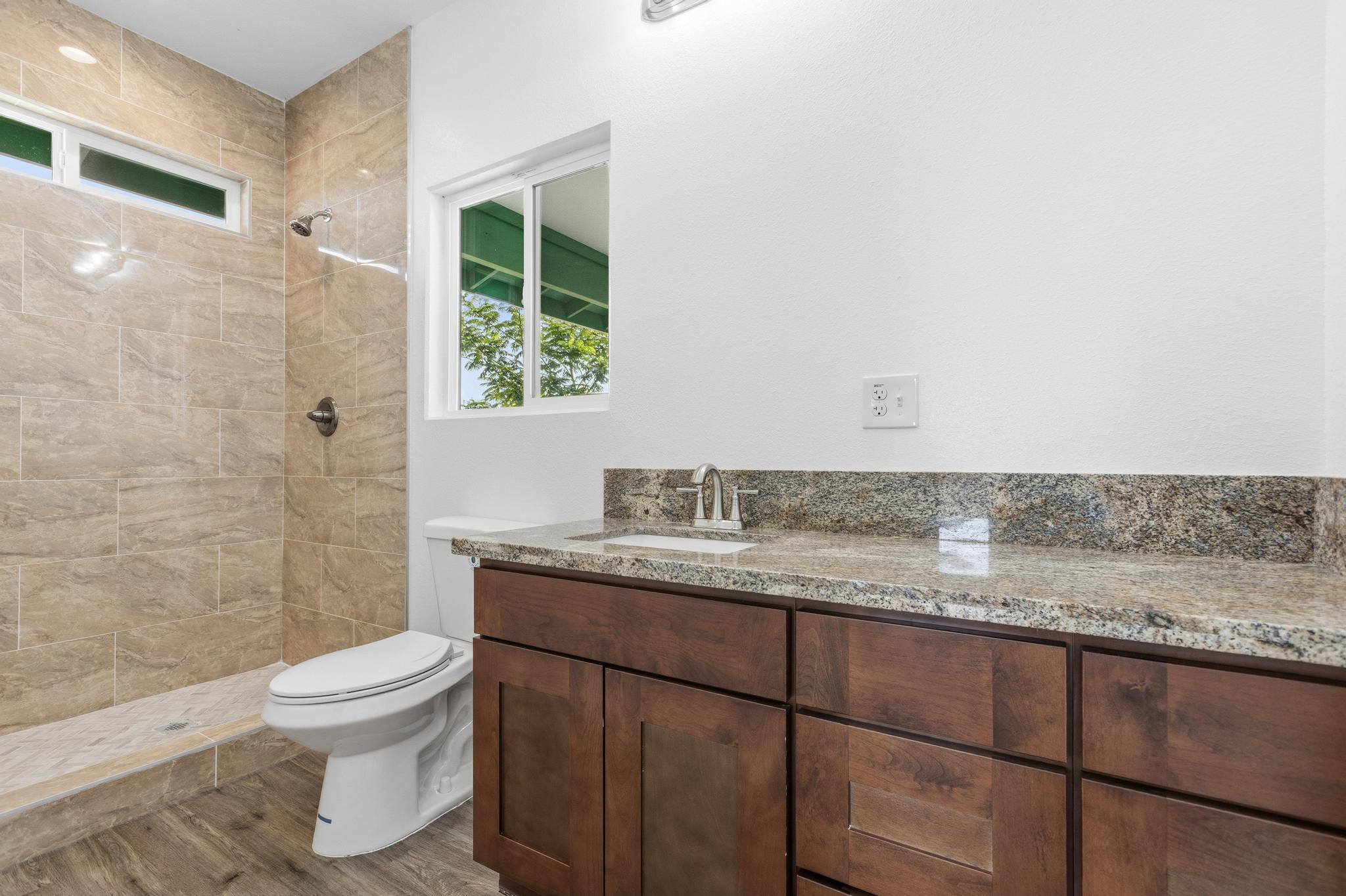 18-7842 Kaniela Road Mountain View, HI 96771 - Photo 16 of 30 a bathroom with a granite countertop sink toilet a mirror and shower
