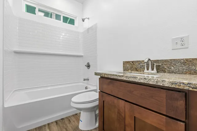 a bathroom with a granite countertop sink a toilet and bathtub