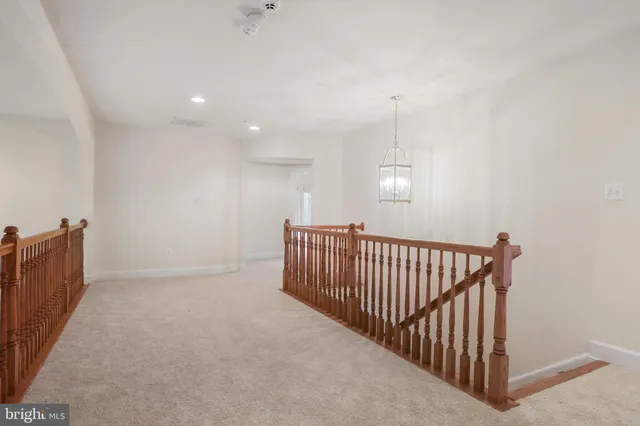 an empty room with chandelier fan and windows