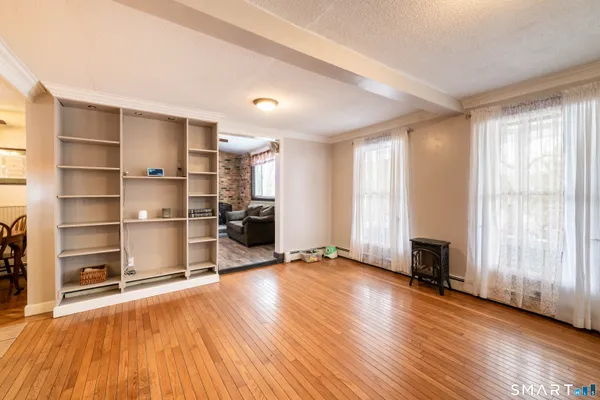 a view of an empty room with a window and wooden floor