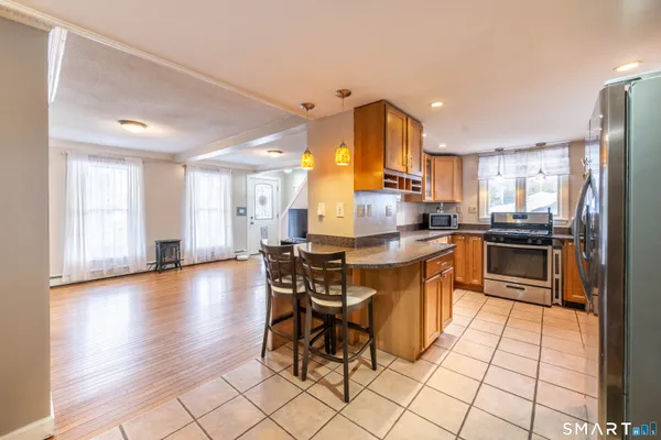 a kitchen with stainless steel appliances kitchen island granite countertop a sink cabinets and wooden floor