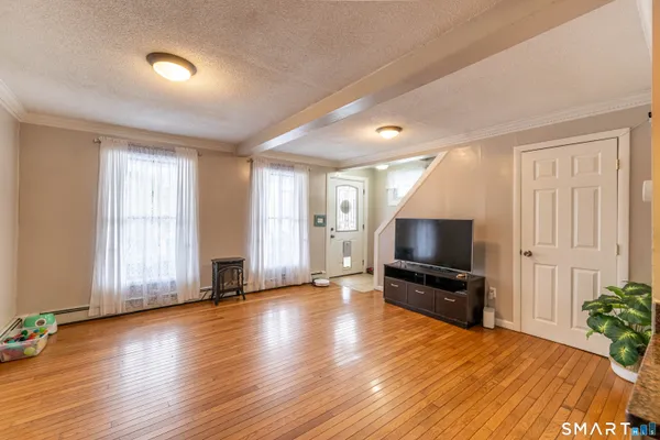 a view of a livingroom with a flat screen tv wooden floor and windows