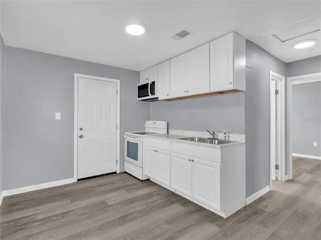 a kitchen with white cabinets and sink