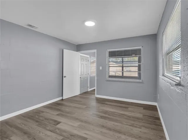 a view of an empty room with wooden floor and a window