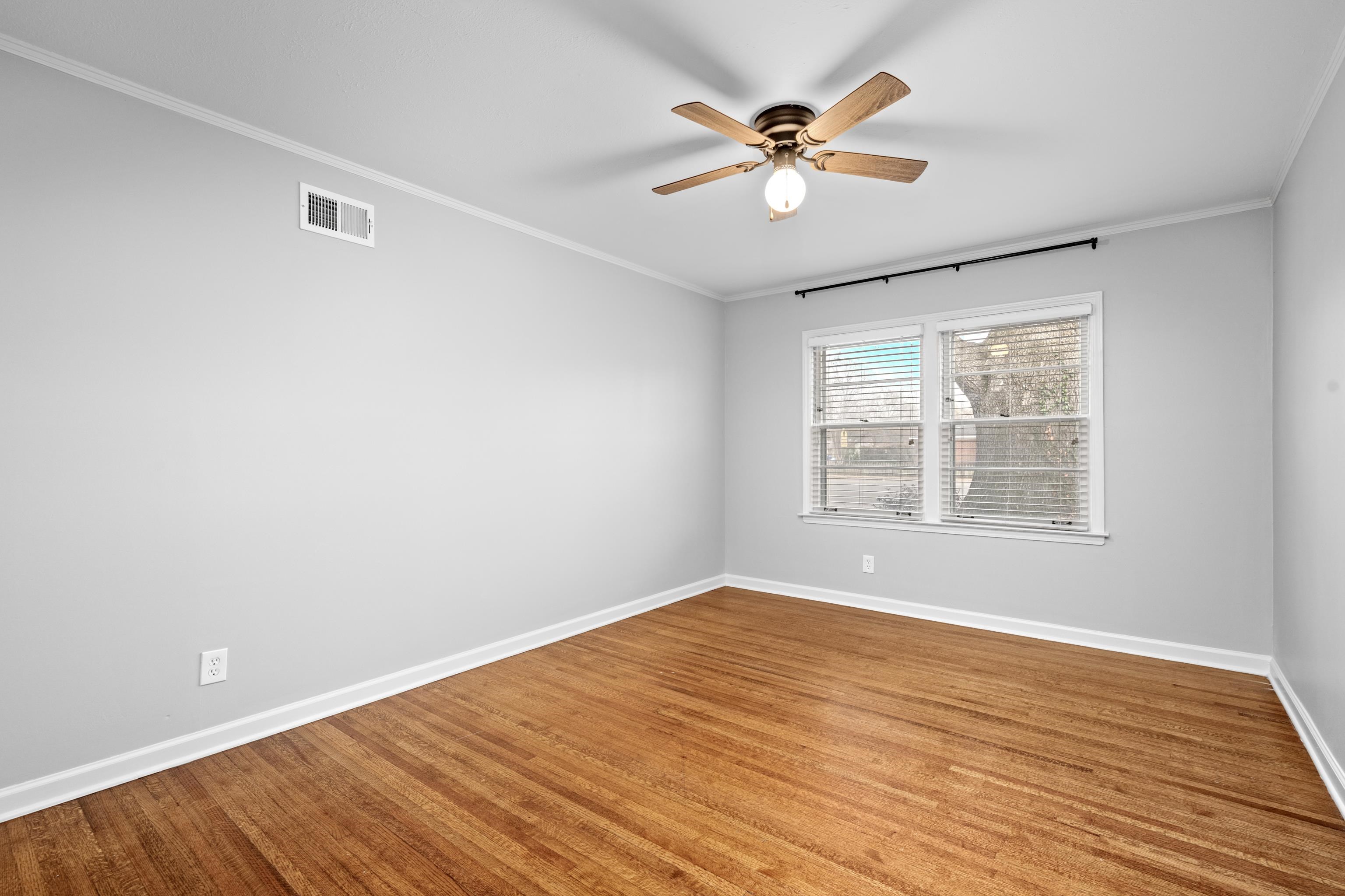 1453 Colonial Road Memphis, TN 38117 - Photo 16 of 36 a view of an empty room with wooden floor and a window
