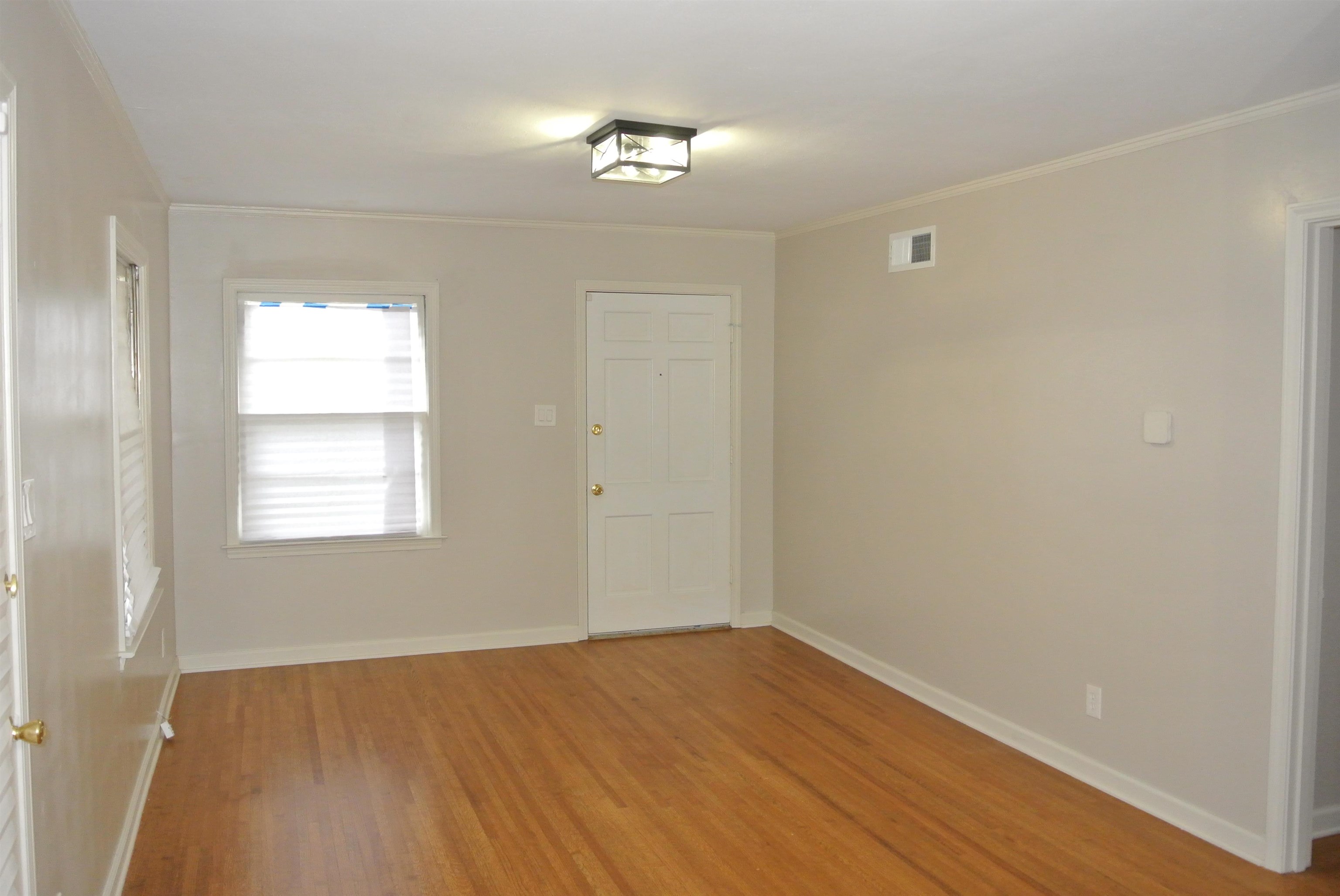 1453 Colonial Road Memphis, TN 38117 - Photo 3 of 19 a view of an empty room with wooden floor and a window