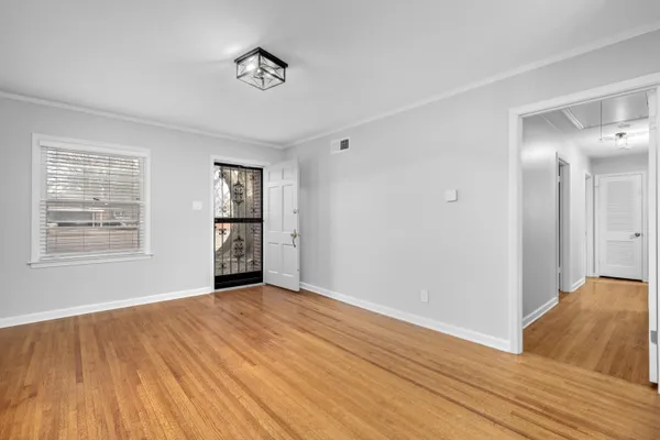a view of an empty room with window and wooden floor