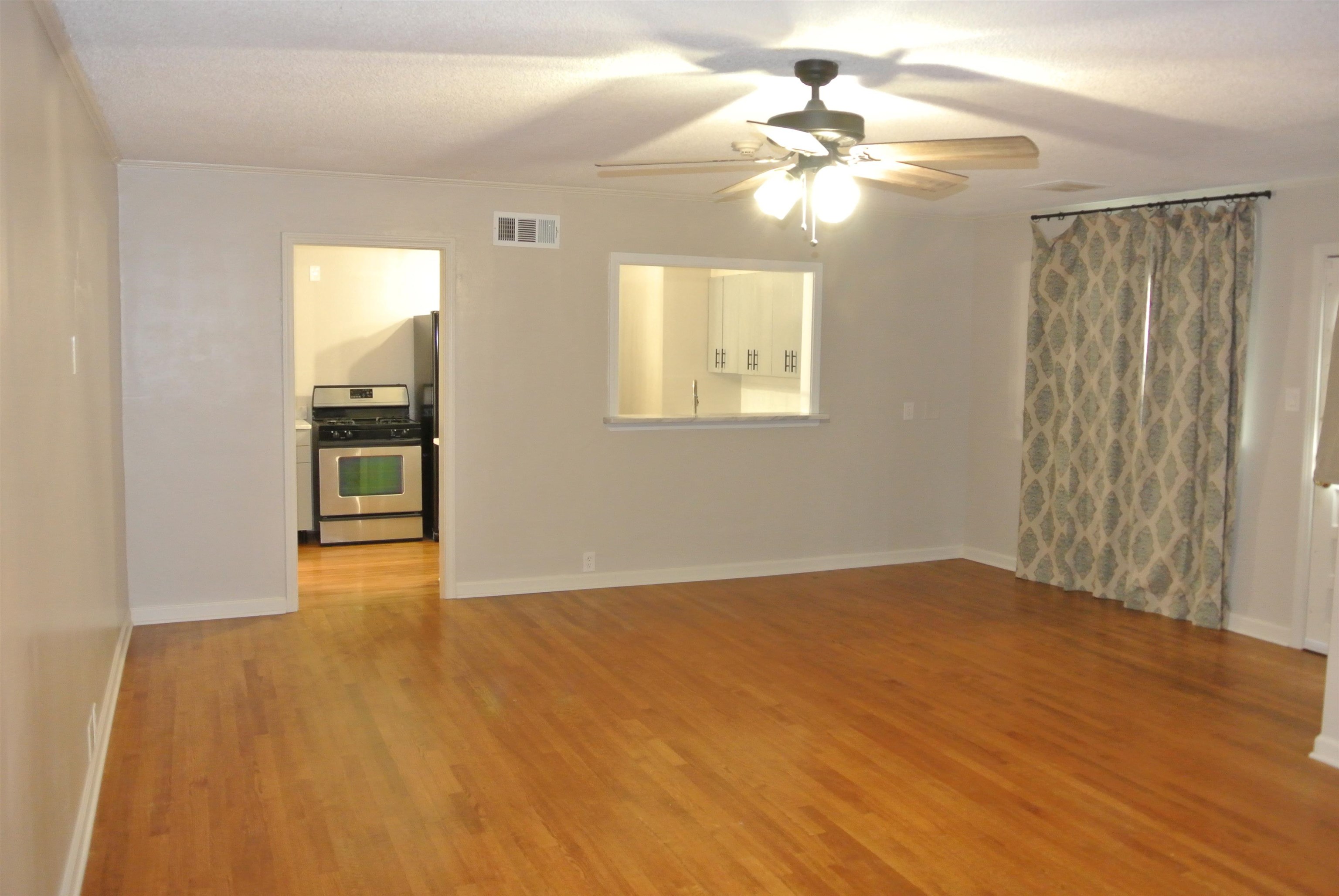 1453 Colonial Road Memphis, TN 38117 - Photo 8 of 19 an empty room with wooden floor chandelier fan and windows