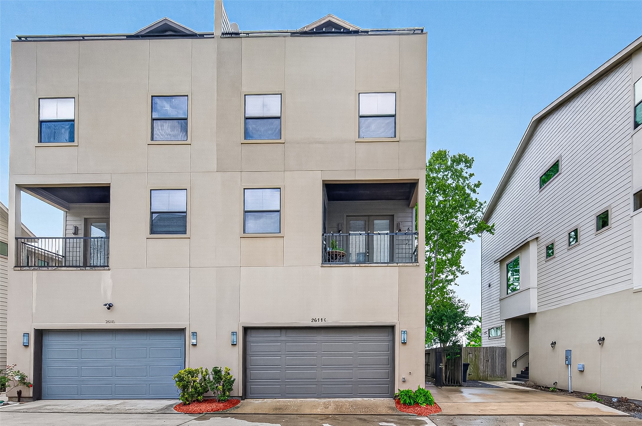 2611 Riverside Drive, Unit C Houston, TX 77004 - Photo 44 of 50 Modern three-story townhouse with a clean facade, featuring two balconies and two garage doors. The home is situated in a compact urban setting with neighboring houses.