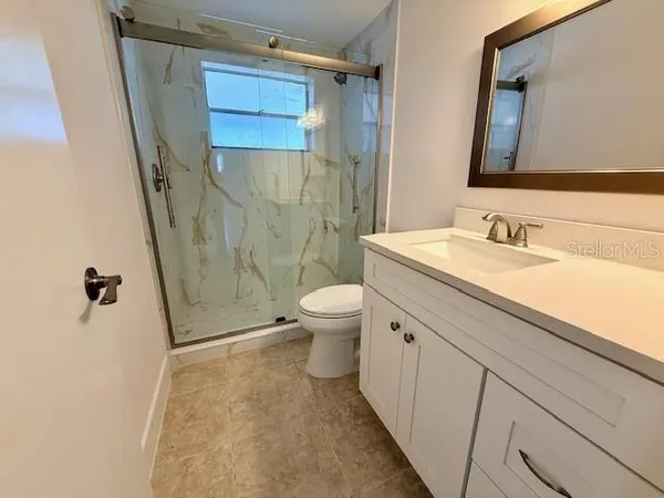 a bathroom with a sink a toilet a mirror and shower
