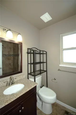 a bathroom with a granite countertop toilet a sink and a mirror