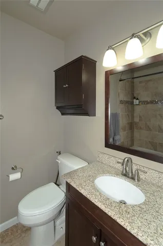 a bathroom with a granite countertop toilet sink and mirror
