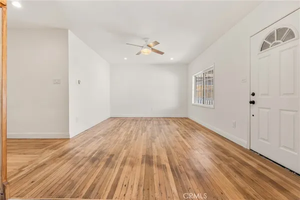 an empty room with wooden floor ceiling fan and windows