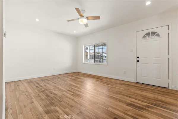 an empty room with wooden floor and ceiling fan