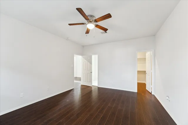 an empty room with wooden floor and ceiling fan