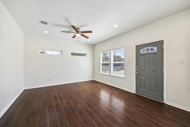 a view of empty room with wooden floor and fan