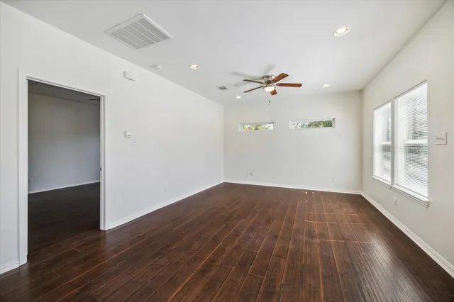 an empty room with wooden floor and windows