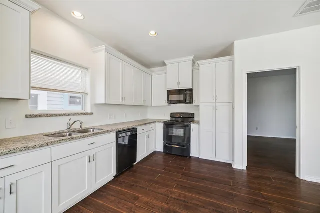 a kitchen with granite countertop white cabinets and wooden floor