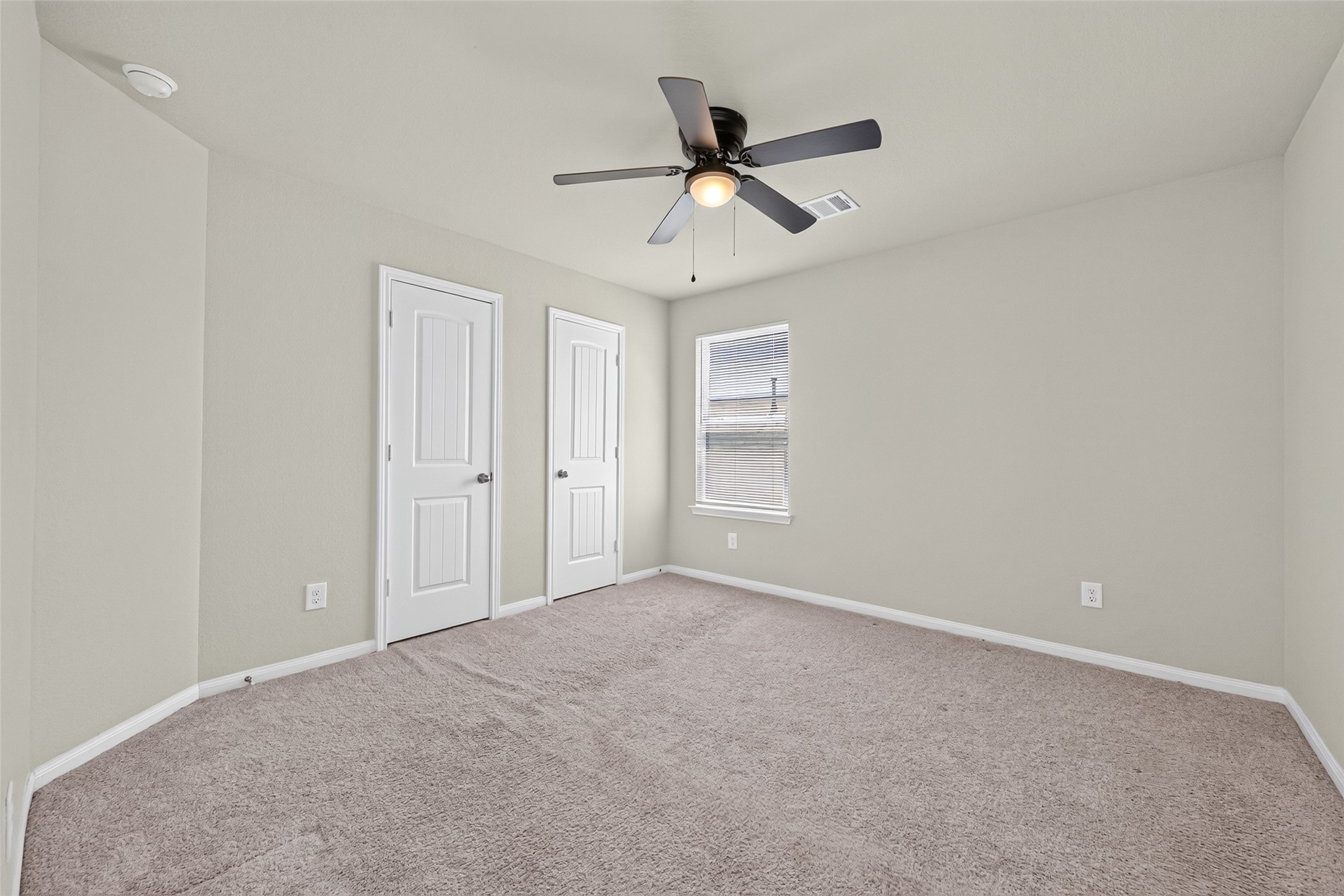 2526 Sturgeon Way Conroe, TX 77384 - Photo 31 of 49 This room features neutral walls, carpeted flooring, a ceiling fan, a window for natural light, and two white doors, ideal for a bedroom or office space.