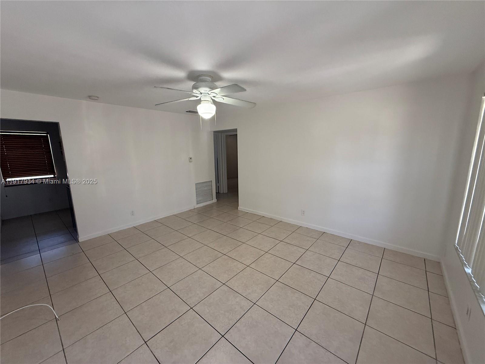 521 Southwest 9th Street, Unit 2 Hallandale Beach, FL 33009 - Photo 2 of 10 an empty room with chandelier fan and windows