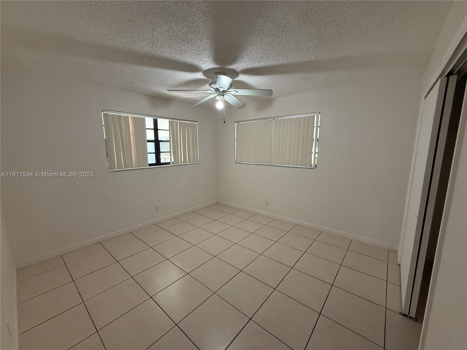 521 Southwest 9th Street, Unit 2 Hallandale Beach, FL 33009 - Photo 3 of 10 an empty room with windows and fan