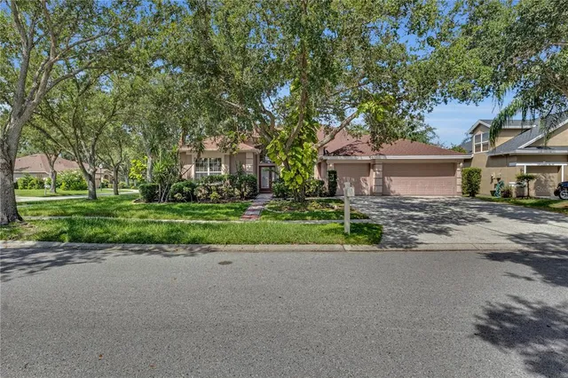 a view of a house with a big yard and large trees