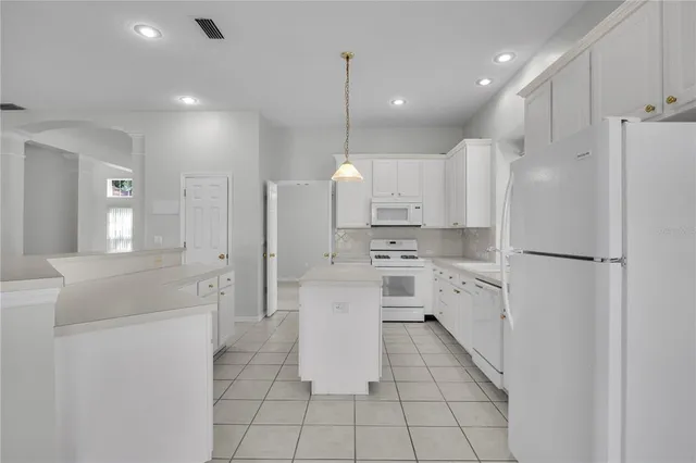 a kitchen with kitchen island white cabinets and refrigerator