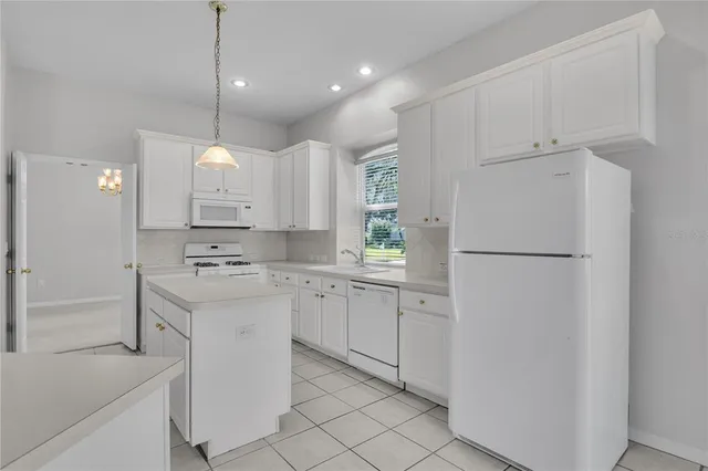 a view of an empty room with kitchen and window