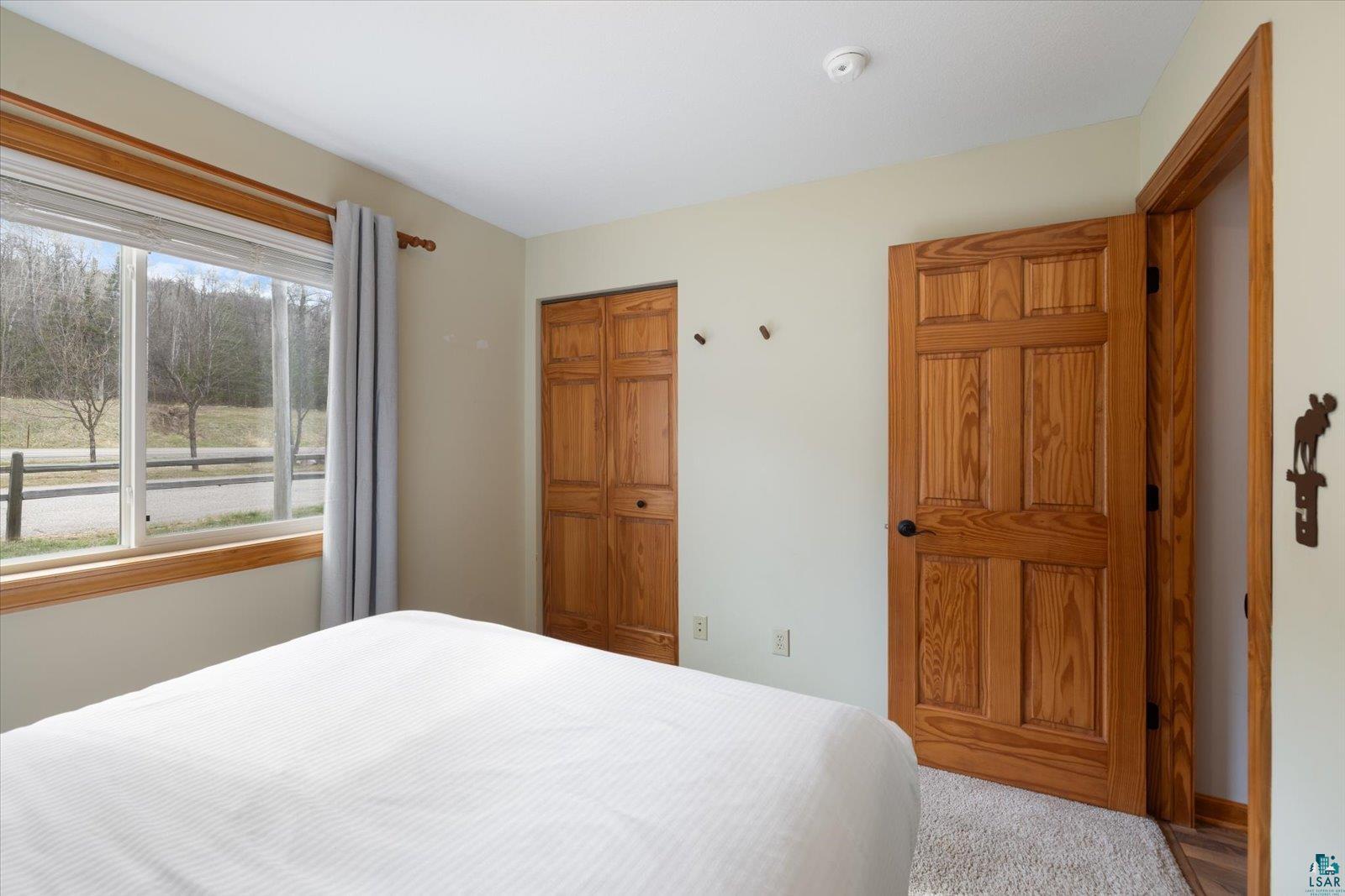 6266 Giants Ridge Road Biwabik, MN 55705 - Photo 26 of 37 Interior room featuring a large window with wood-finish trim, a paneled wood-finish door, and wood-finish bifold closet doors