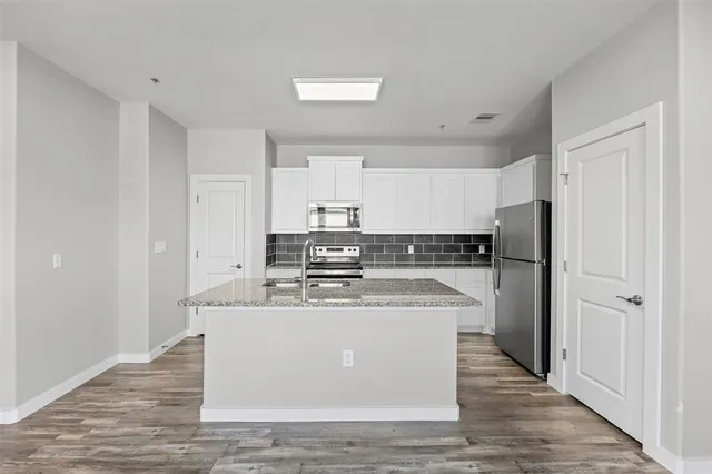 a view of a kitchen with a refrigerator and a wooden floor