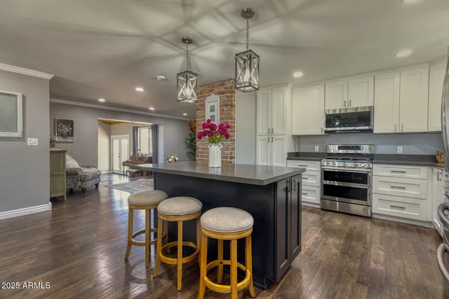 a kitchen with granite countertop a stove a sink dishwasher a dining table and chairs with wooden floor