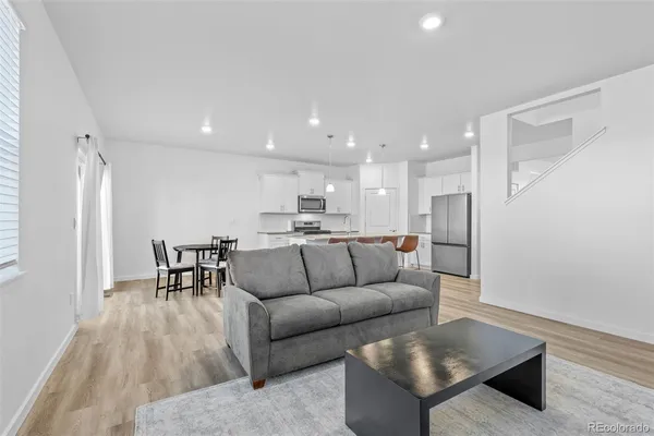 a kitchen with stainless steel appliances granite countertop a refrigerator a stove a sink a dining table and chairs with wooden floor