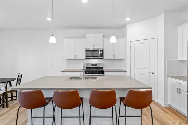 a kitchen with stainless steel appliances a stove a sink a table and chairs