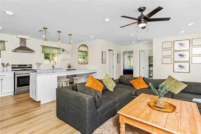 a kitchen with granite countertop a refrigerator a stove a sink and white cabinets with wooden floor