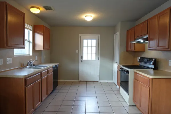 a kitchen with a sink a stove top oven and a refrigerator