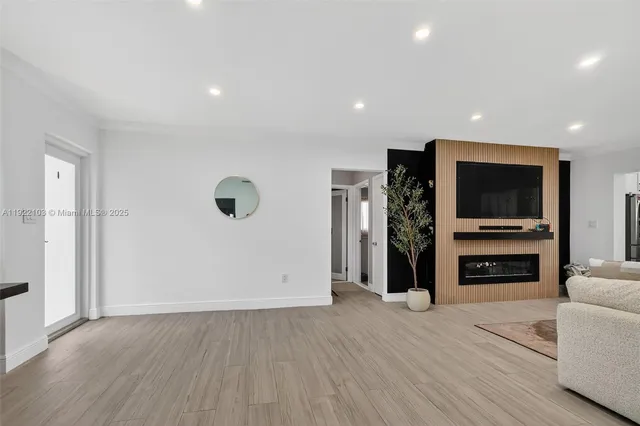 a view of a livingroom with a flat screen tv wooden floor and a ceiling fan
