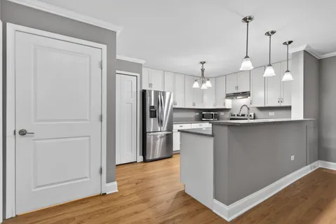 a kitchen with kitchen island white cabinets and stainless steel appliances