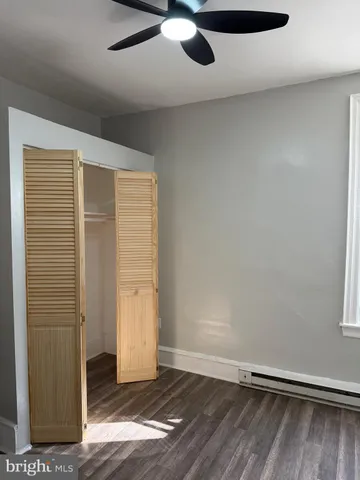 an empty room with wooden floor cabinet and windows