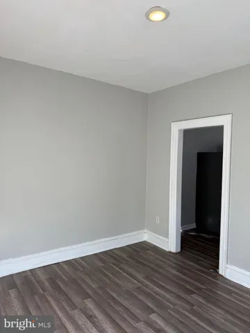 a view of an empty room with wooden floor and closet