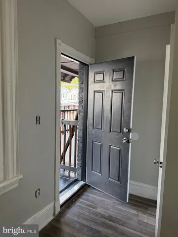 an entryway at an empty room with wooden floor and a window