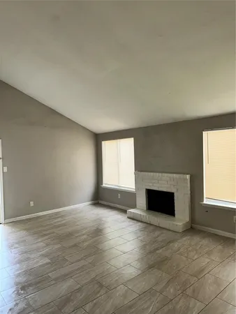 an empty room with windows and fireplace